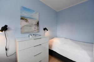 ein Schlafzimmer mit einer weißen Kommode und einem Bett in der Unterkunft "Appartementhaus Deichgraf" Appartement D450 in Döse