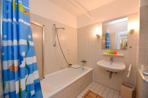 ein Badezimmer mit Badewanne, Waschbecken und Dusche in der Unterkunft "Appartementhaus Deichgraf" Appartement D450 in Döse