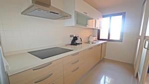 eine Küche mit Holzschränken, einem Waschbecken und einem Fenster in der Unterkunft APARTAMENTO NUEVA RIBERA REF: 6030 in Los Alcázares
