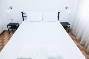 een wit bed met 2 stoelen in een kamer bij Beautifull Apartment in Piraeus in Piraeus