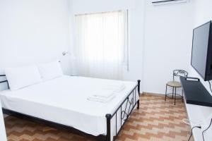a bedroom with a white bed and a flat screen tv at Beautifull Apartment in Piraeus in Piraeus