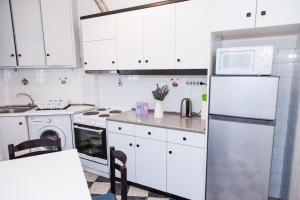 a kitchen with white cabinets and a white refrigerator at Beautifull Apartment in Piraeus in Piraeus