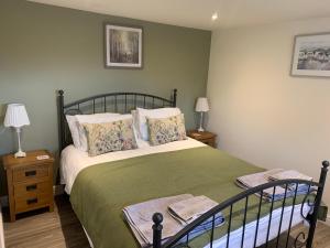 ein Schlafzimmer mit einem Bett mit einer grünen Decke und Kissen in der Unterkunft The Granary at Pentregaer Ucha, tennis court & lake. in Oswestry