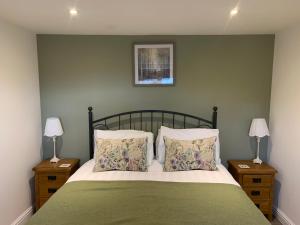 ein Schlafzimmer mit einem Bett mit zwei Nachttischen und zwei Lampen in der Unterkunft The Granary at Pentregaer Ucha, tennis court & lake. in Oswestry