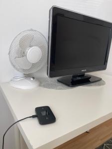 un monitor de ordenador y un ventilador en un escritorio en Yksiö kilometri jokirannasta föriltä, en Turku