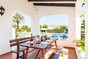 a dining room with a table and chairs and a pool at Villa Mercedes by Villa Plus in Cala en Forcat