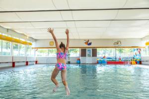 a girl jumping into the water in a swimming pool at EuroParcs Poort van Maastricht in Berg en Terblijt