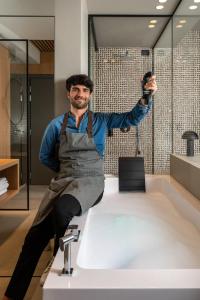 a man sitting on a sink holding a camera at Hotel San Marco in Cattolica