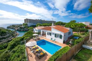 a house with a swimming pool next to the ocean at Villa Nereida by Villa Plus in Cala en Forcat