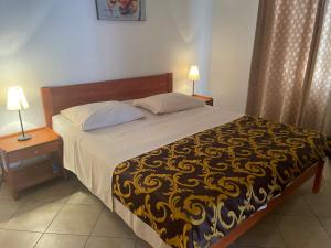 a bedroom with a bed with a yellow and black blanket at Apartments Iva in Pakoštane