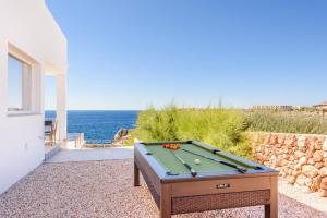 a pool table on a gravel patio with the ocean at Villa Aguamarina by Villa Plus in Cala en Forcat