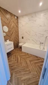 a bathroom with a white tub and a wooden floor at RYNEK 2 DUKLA- POKOJE I APARTAMENTY in Dukla