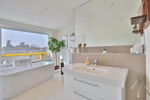 een witte badkamer met een wastafel en een raam bij Strandallee 10 Penthouse Seaview in Haffkrug