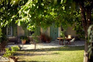 eine Terrasse mit einem Tisch, Stühlen und einer grünen Tür in der Unterkunft Hotel Moulin d'Aure in Saint-Rémy-de-Provence