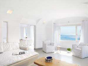 a white living room with a couch and two chairs at Mykonos Blu, A Grecotel Resort to Live in Psarou