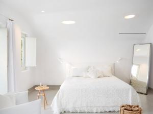 a white bedroom with a white bed and a mirror at Mykonos Blu, A Grecotel Resort to Live in Psarou
