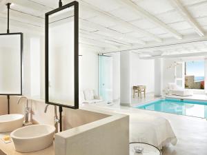 a bathroom with a mirror and a swimming pool at Mykonos Blu, A Grecotel Resort to Live in Psarou