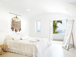 a white bedroom with a bed and a mirror at Mykonos Blu, A Grecotel Resort to Live in Psarou