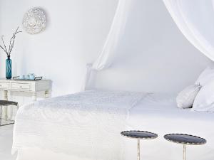 a white bedroom with a white bed and a table at Mykonos Blu, A Grecotel Resort to Live in Psarou