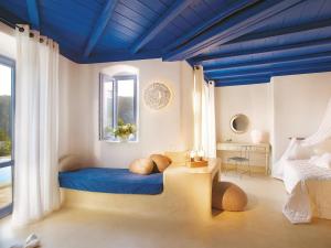 a room with a bed with a blue ceiling at Mykonos Blu, A Grecotel Resort to Live in Psarou