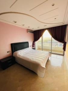 a bedroom with a large bed with a large window at Very nice apartment near the city center & beach in Agadir