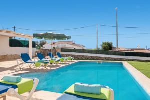 a swimming pool with chairs and umbrellas next to a house at Villa Santi III by Villa Plus in Cala'n Porter