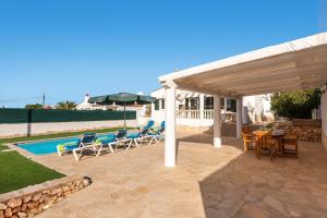 a pavilion with chairs and a table and a pool at Villa Santi III by Villa Plus in Cala'n Porter