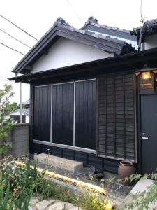 ein schwarzes und weißes Haus mit einer schwarzen Tür in der Unterkunft Tomo's INN - priceless experience - in Obu