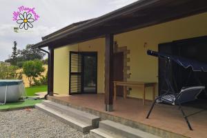 ein gelbes Haus mit einem Tisch und einem Stuhl auf einer Veranda in der Unterkunft VILLA MARGHERITA in Rogiano Gravina