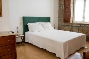 a bedroom with a large bed with a green headboard at Quinta do Reconco in Santa Eugénia