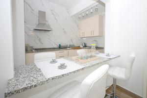 a white kitchen with a table and white chairs at B50 - Main Square Apartment in Lagos in Lagos