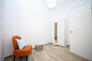 an orange chair in a white room with a door at B50 - Main Square Apartment in Lagos in Lagos