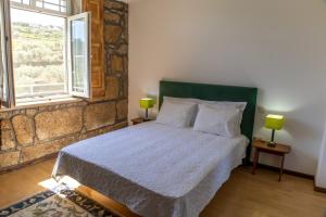 a bedroom with a bed with two lamps on two tables at Quinta do Reconco in Santa Eugénia