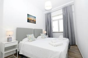 a white bedroom with two beds and a window at B50 - Main Square Apartment in Lagos in Lagos