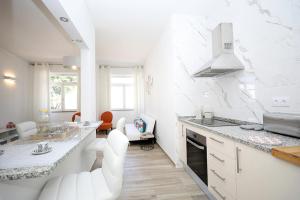 a white kitchen with white chairs and a counter at B50 - Main Square Apartment in Lagos in Lagos