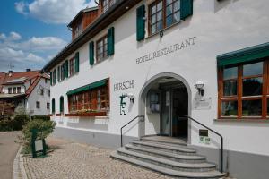 ein weißes Gebäude mit einer Treppe, die zu einer Tür führt in der Unterkunft Romantik Hotel & Restaurant Hirsch in Sonnenbühl