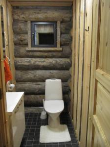 a bathroom with a toilet in a log wall at Revontuli Cottage in Kolari