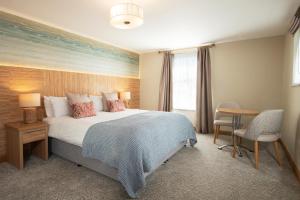 a bedroom with a bed and a table and chairs at Fistral Beach Hotel and Spa - Adults Only in Newquay