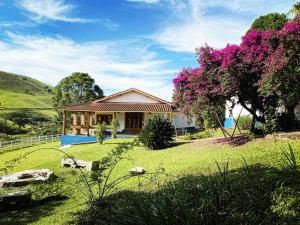 une maison dans un champ avec un arbre et des fleurs roses dans l'établissement Flores de Cunha, à Cunha
