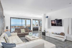 a living room with white furniture and glass windows at Villa Sea View by Villa Plus in Sa Caleta