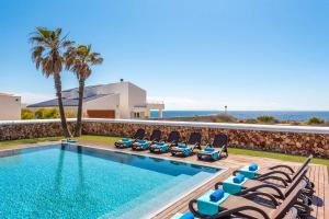 a swimming pool with chairs and the ocean in the background at Villa Sea View by Villa Plus in Sa Caleta