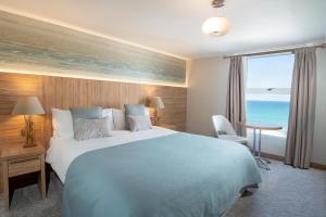 a bedroom with a large bed with a view of the ocean at Fistral Beach Hotel and Spa - Adults Only in Newquay
