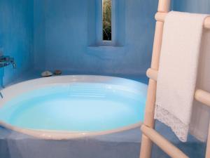 a bath tub in a blue bathroom with a towel at Mykonos Blu, A Grecotel Resort to Live in Psarou