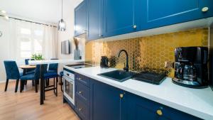 - une cuisine avec des placards bleus, un évier et une table dans l'établissement HELLO Apartamenty Evo - Długa 15, à Jelenia Góra