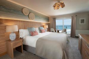 um quarto com uma cama grande e vista para o oceano em Fistral Beach Hotel and Spa - Adults Only em Newquay