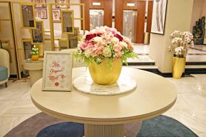 einen Tisch mit einer Vase Blumen und einer Karte in der Unterkunft The George Hotel by Saffron, Dubai Creek in Dubai