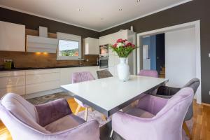 uma cozinha com uma mesa com cadeiras roxas e um vaso de flores em Villa Saric em Bribir