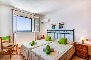 een slaapkamer met 2 bedden met groene kussens en een raam bij Villa Laurel by Villa Plus in Alaior +20 foto's