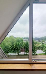 une fenêtre avec vue sur la rivière dans l'établissement Apartment na poddaszu, à Augustów
