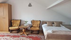 1 dormitorio con 1 cama, 2 sillas y mesa en Apartment na poddaszu, en Augustów